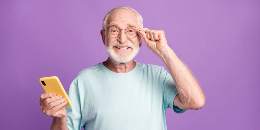 Portret van een gelukkige man met bril en smartphone op een levendige violette achtergrond. Portret van een gelukkige man met bril en smartphone op een levendige violette achtergrond.